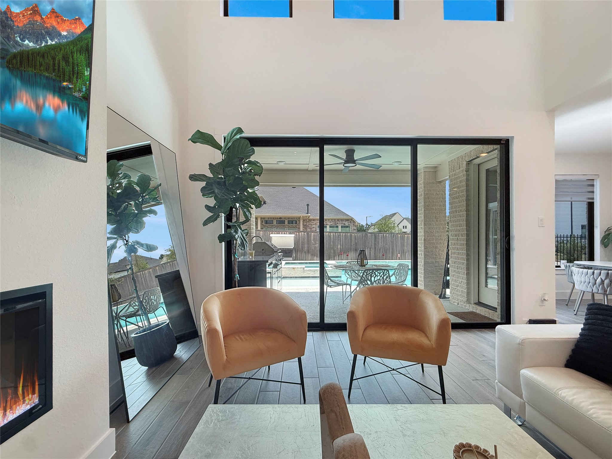 26918 Swanborough Road Spring, TX 77389 - Photo 11 of 50 Inside, soaring ceilings and oversized windows create light, open spaces, anchored by a sleek linear fireplace and seamless sliding glass doors out to the pool and outdoor areas.