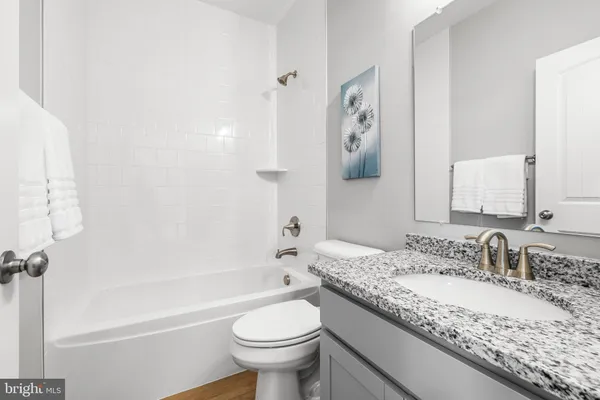 a bathroom with a granite countertop sink a toilet and shower