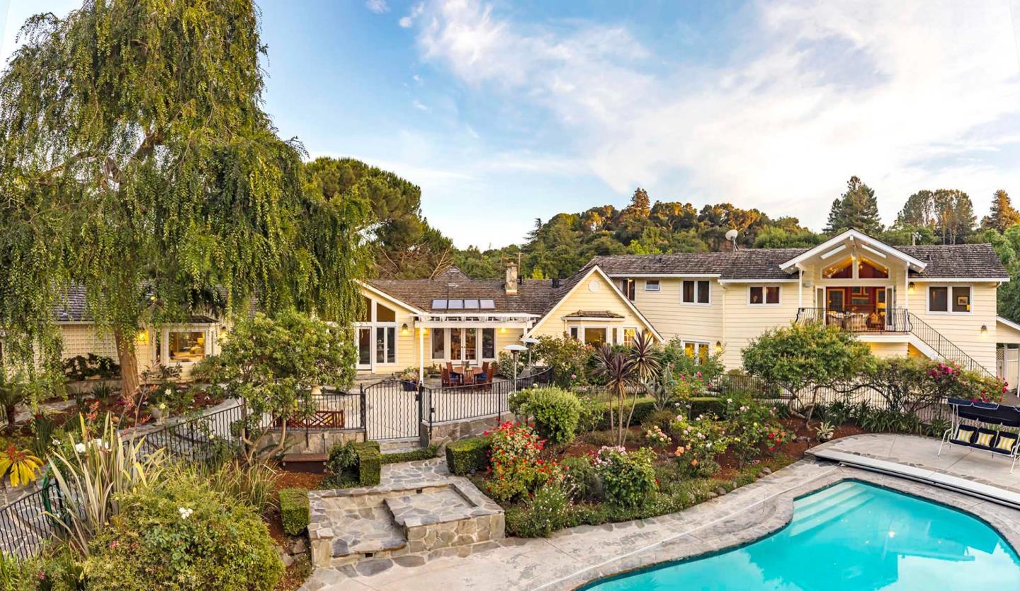 a view of a white house next to a yard with plants and trees