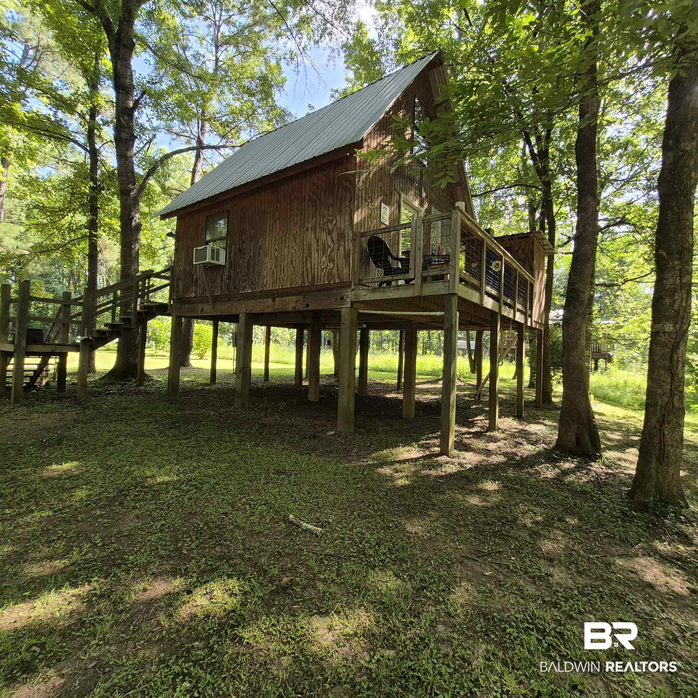 0 Eureka Landing Road Uriah, AL 36480 - Photo 21 of 27 Elevated wooden structure featuring a pitched metal roof, exterior wood siding, a window-mounted air conditioning unit, an exterior deck with cable railings, and an attached staircase with wooden railings