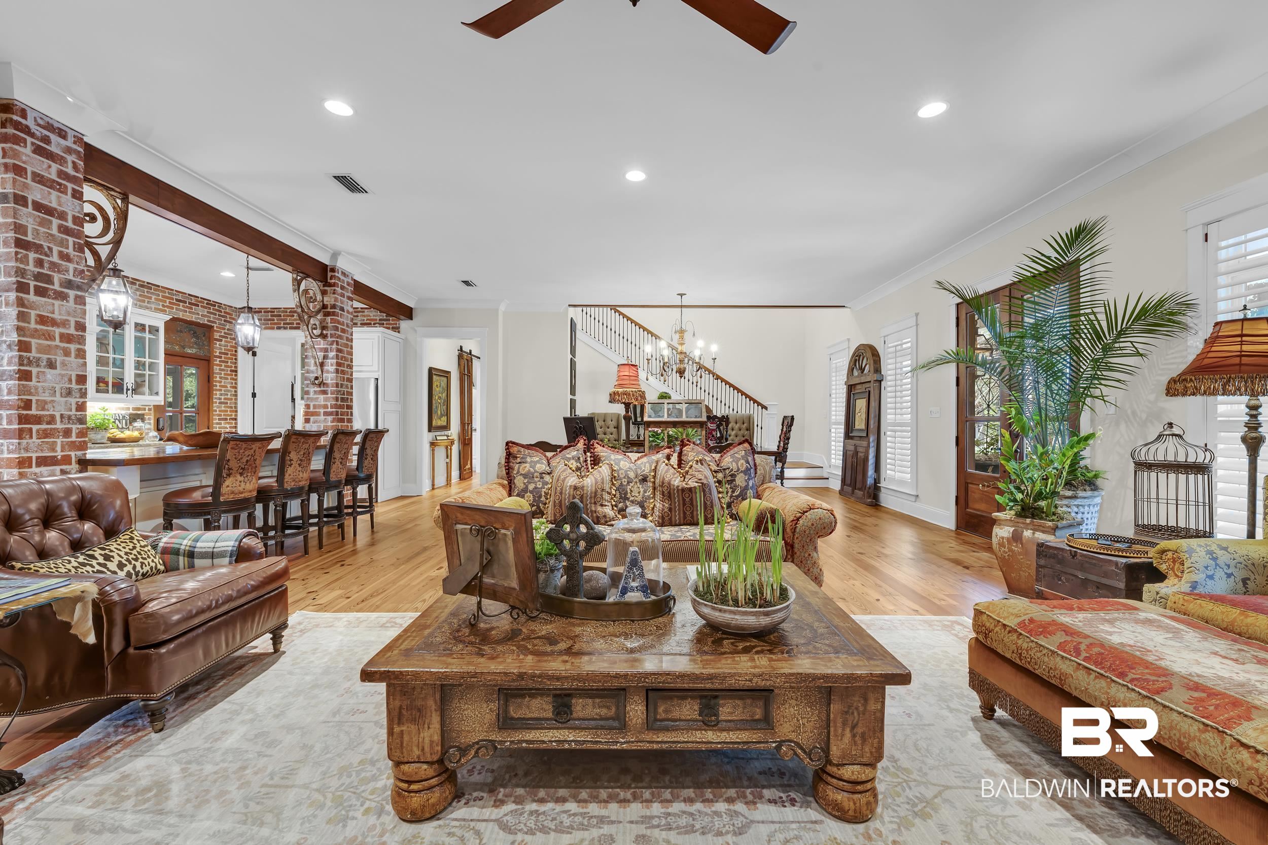 12161 Jessamine Street Magnolia Springs, AL 36555 - Photo 6 of 70 Living area featuring plenty of natural light, suspended lighting, a ceiling fan, ornamental molding, and brick wall