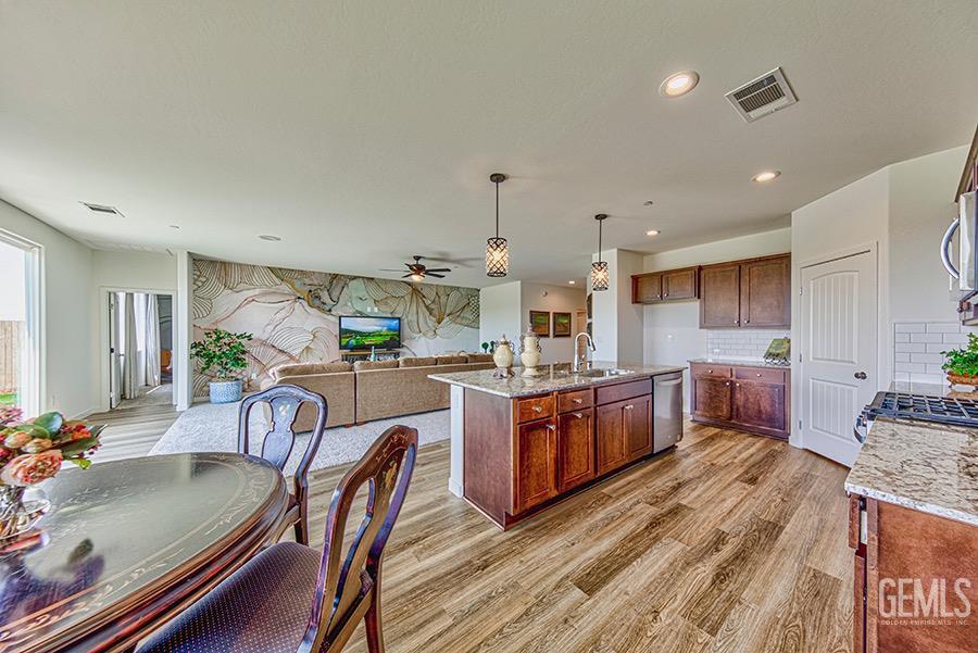 Undisclosed Address Bakersfield, CA 93311 - Photo 2 of 11 a large kitchen with kitchen island a large island a stove a sink a dining table and chairs