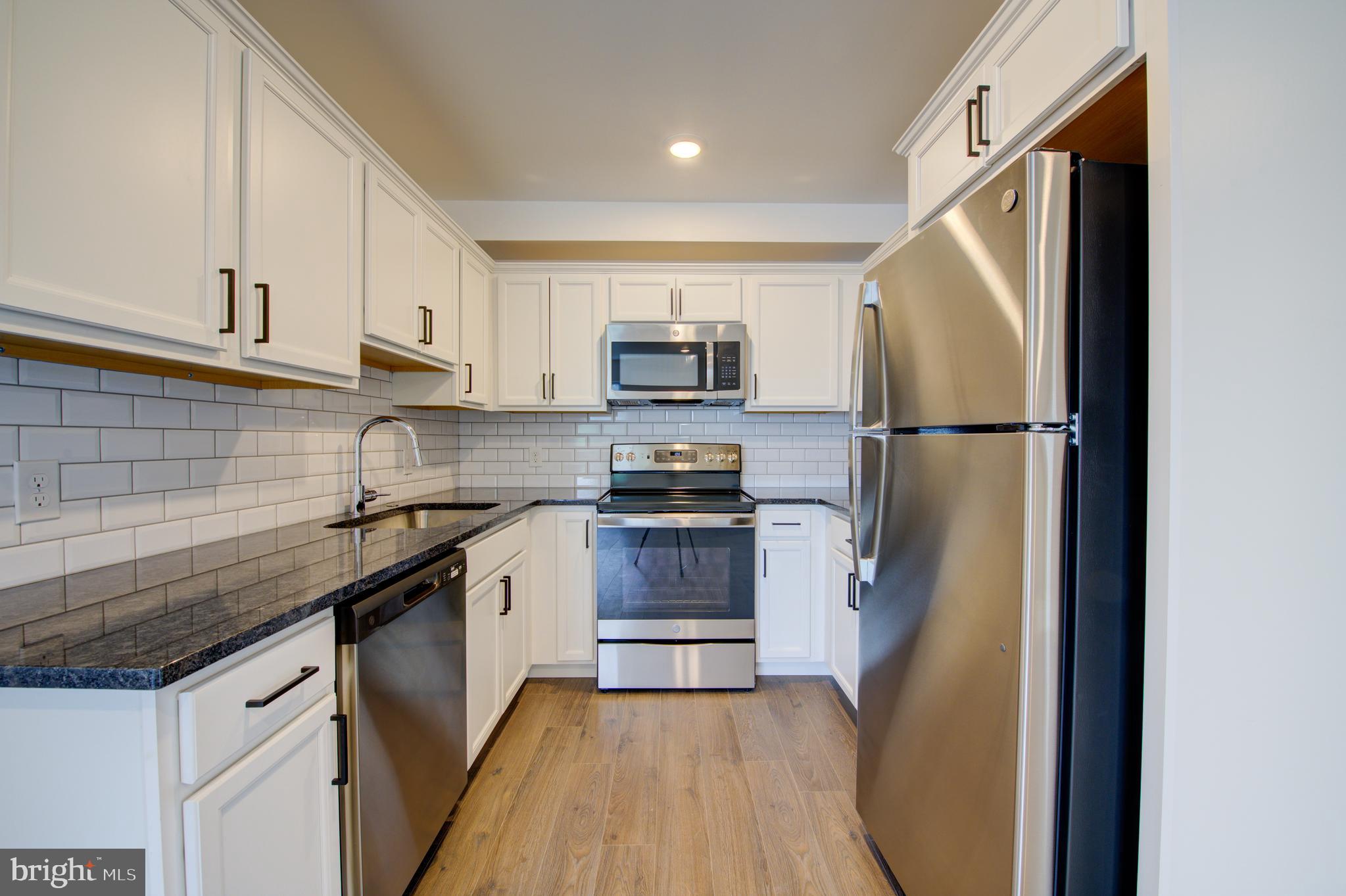 a kitchen with granite countertop a refrigerator stove and sink