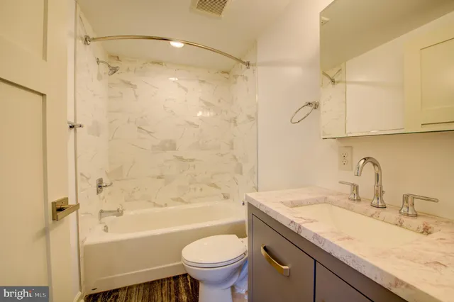 a bathroom with a granite countertop sink toilet and shower