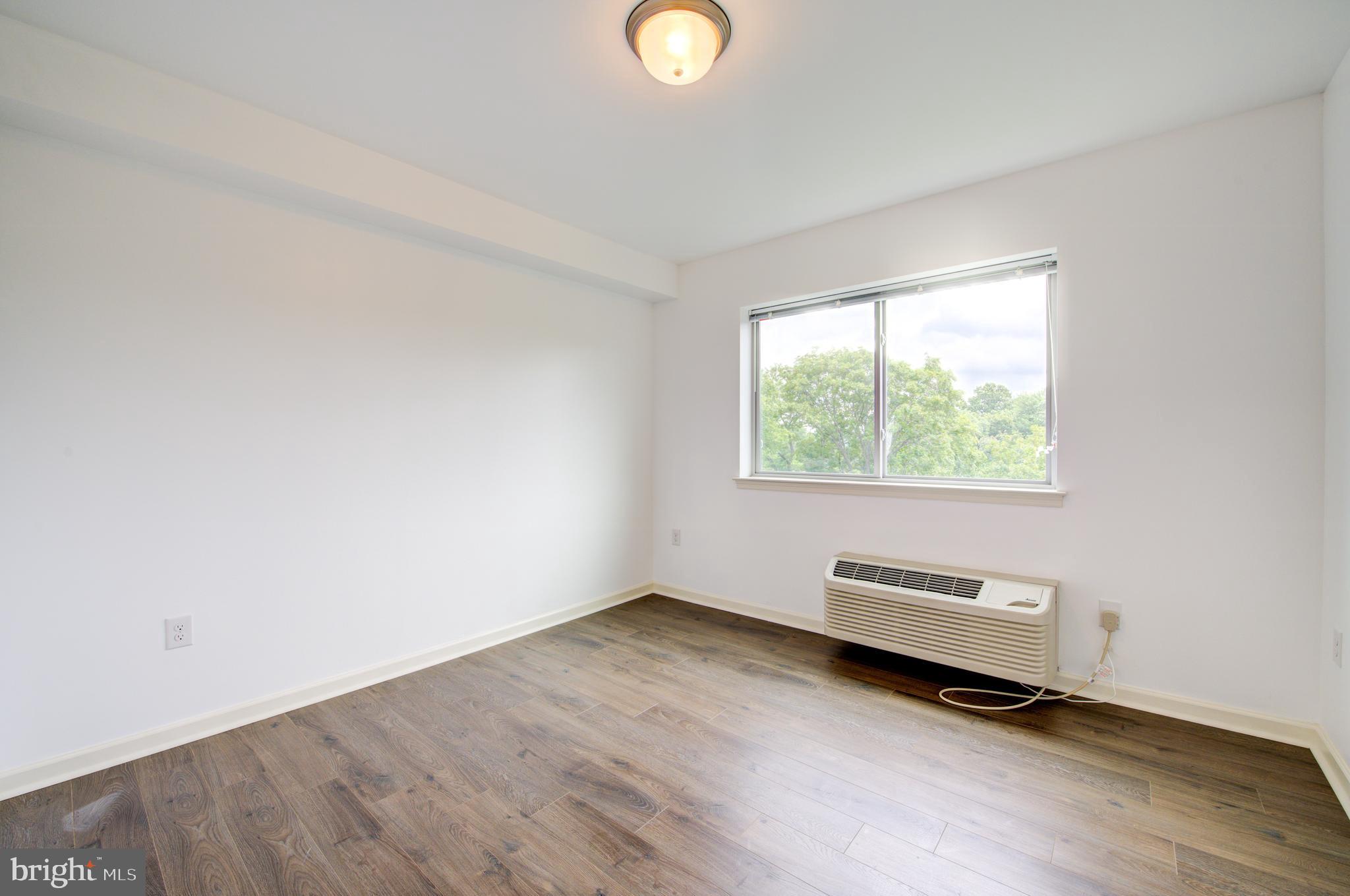 6649 Ridge Avenue, Unit B103 Philadelphia, PA 19128 - Photo 6 of 14 an empty room with wooden floor and windows