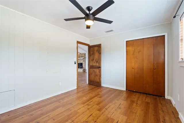 an empty room with wooden floor and a ceiling fan