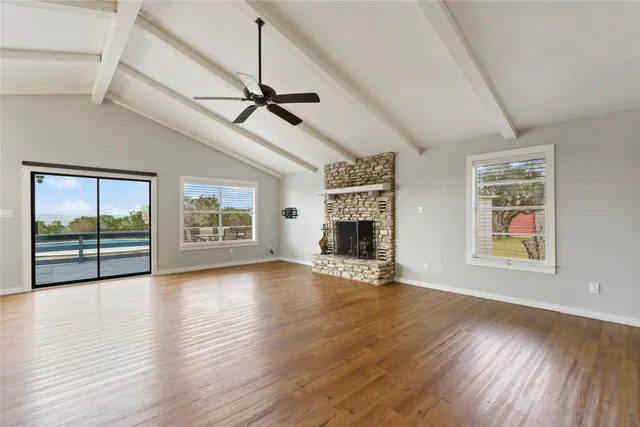 a view of an empty room with wooden floor fireplace and a window