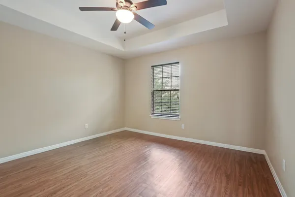 an empty room with wooden floor fan and windows
