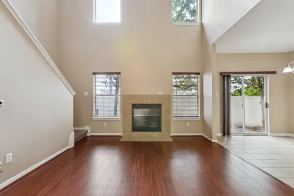 an empty room with wooden floor windows and fireplace
