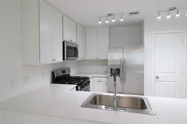 a kitchen with a sink a refrigerator and cabinets