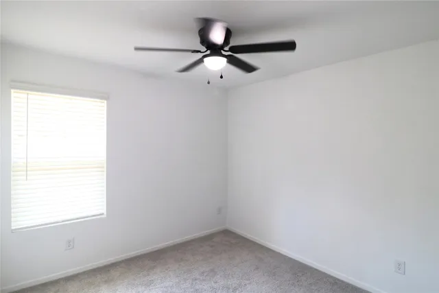 an empty room with a window and a fan