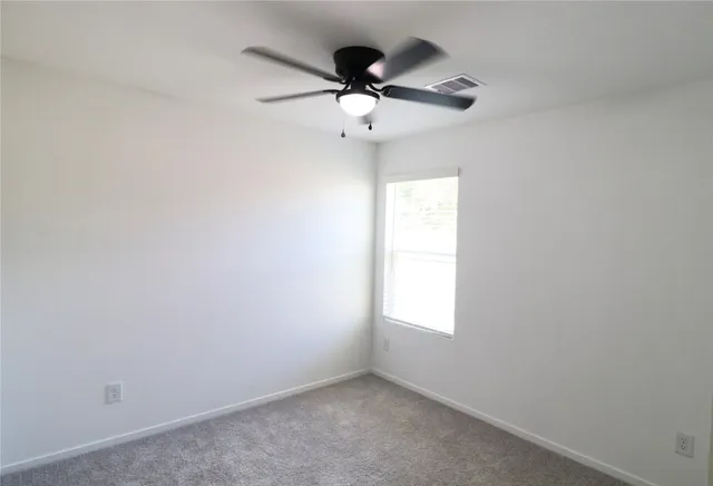 an empty room with window and ceiling fan