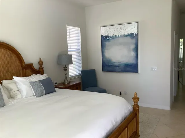 a bedroom with a bed and a lamp on dresser