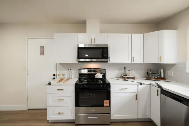 a kitchen with white cabinets and appliances