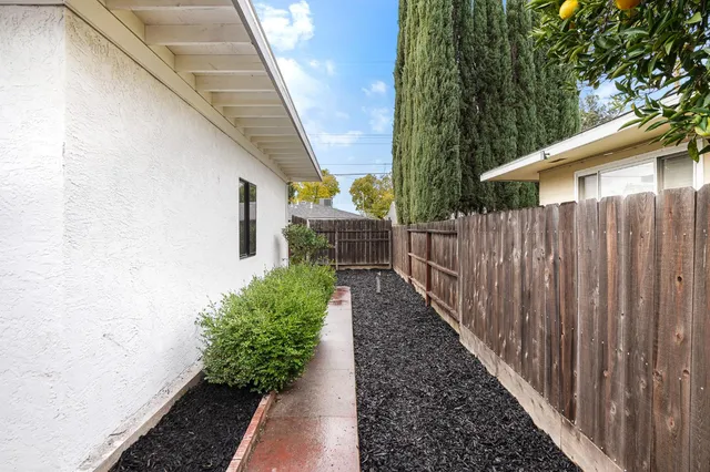 a view of a pathway of a white house with wooden fence