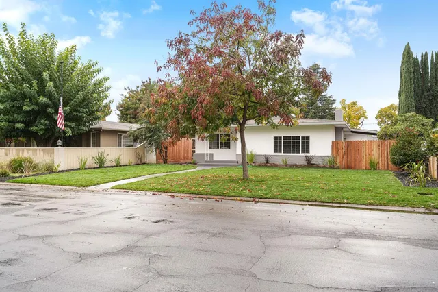a view of a house with a yard and large trees