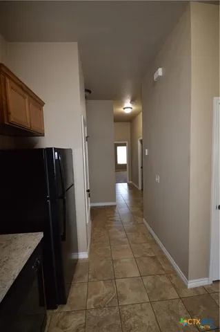 a view of a refrigerator in kitchen and an empty room