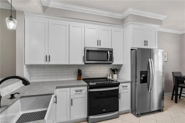 a kitchen with stainless steel appliances granite countertop a refrigerator stove and white cabinets
