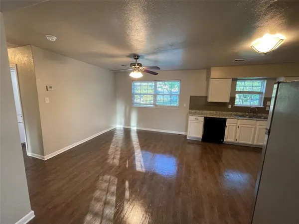 an empty room with wooden floor fireplace and windows