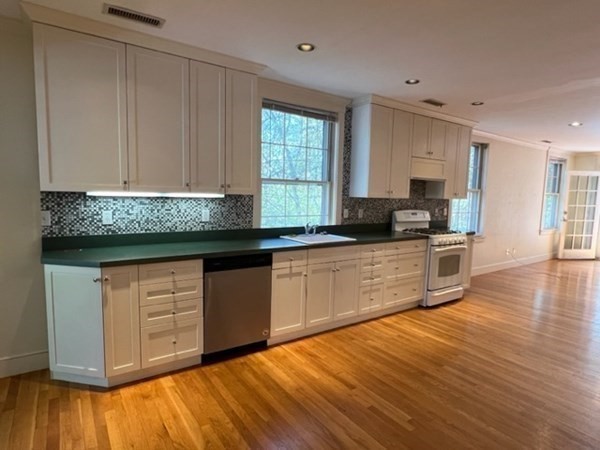 a kitchen with granite countertop a sink window and cabinets