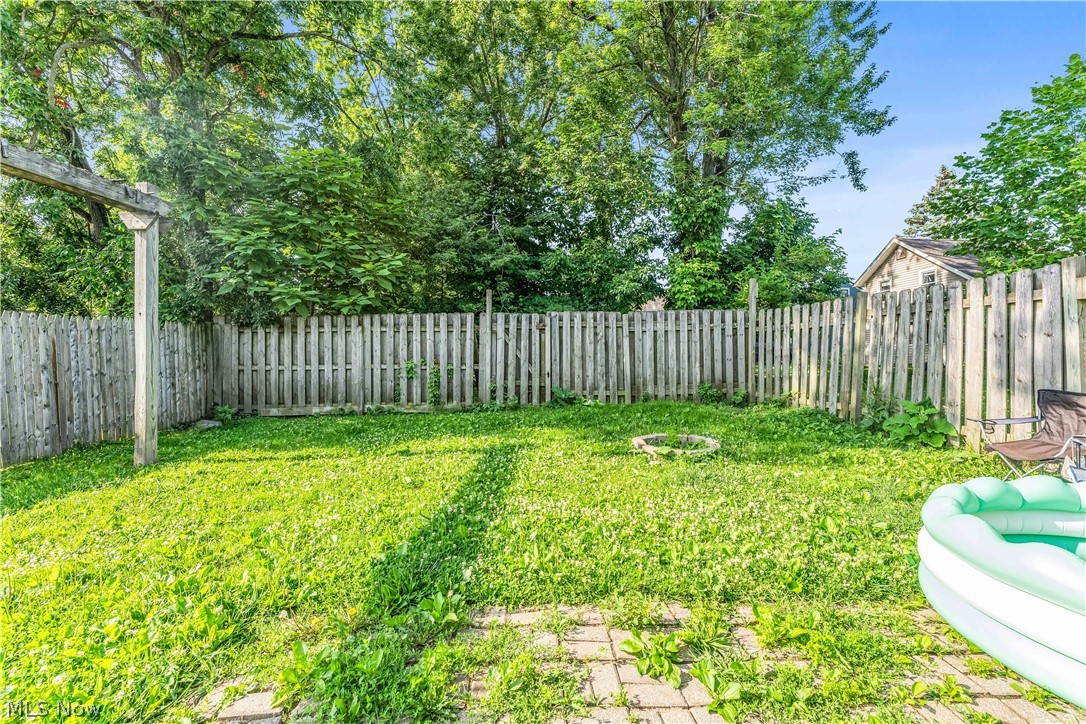 422 West Smith Road Medina, OH 44256 - Photo 27 of 29 Grassed backyard with wood privacy fencing, mature trees, and a ground-level fire pit