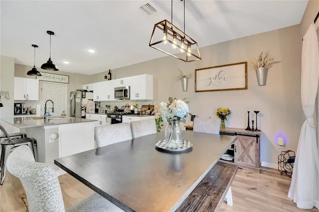 a kitchen with a dining table wooden floor and stainless steel appliances