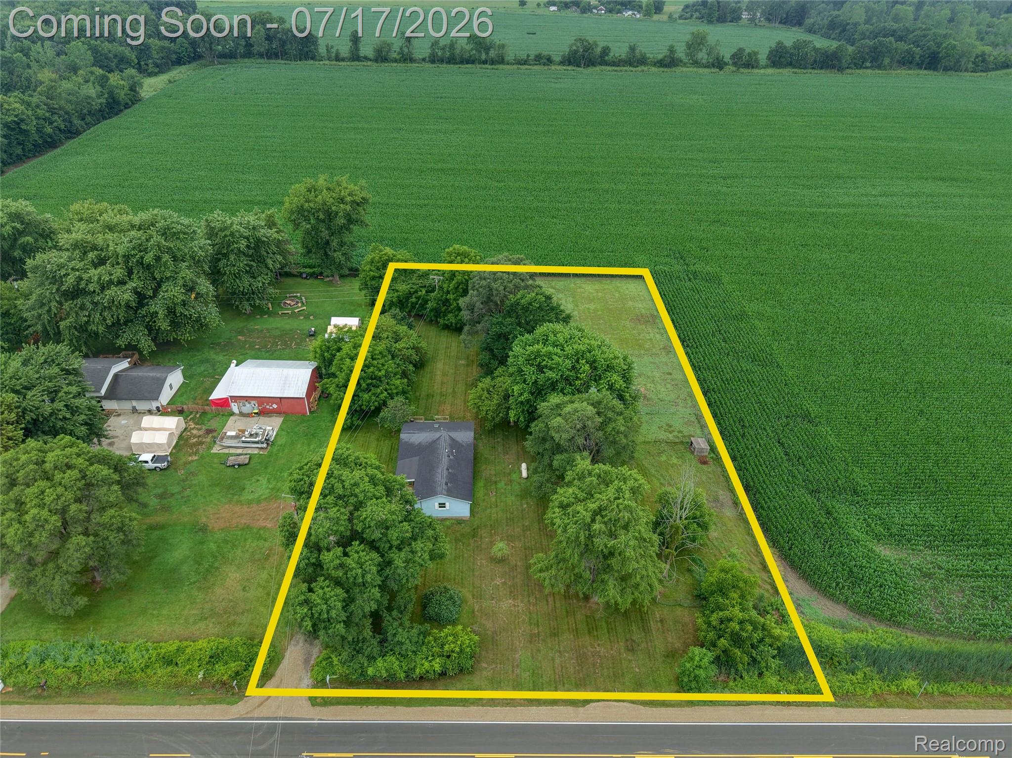 9204 Bray Road Millington, MI 48746 - Photo 13 of 14 Expansive agricultural land featuring a single-story residence with a dark roof, surrounded by mature trees and verdant fields