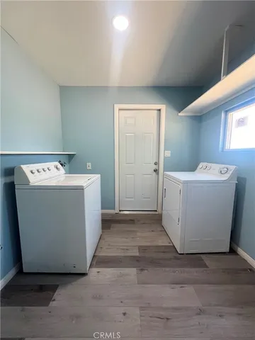 a utility room with a washer dryer with white wooden cabinets