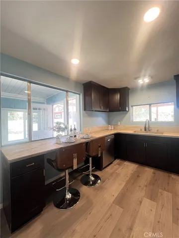 a kitchen with a sink dishwasher a stove and black cabinets with wooden floor