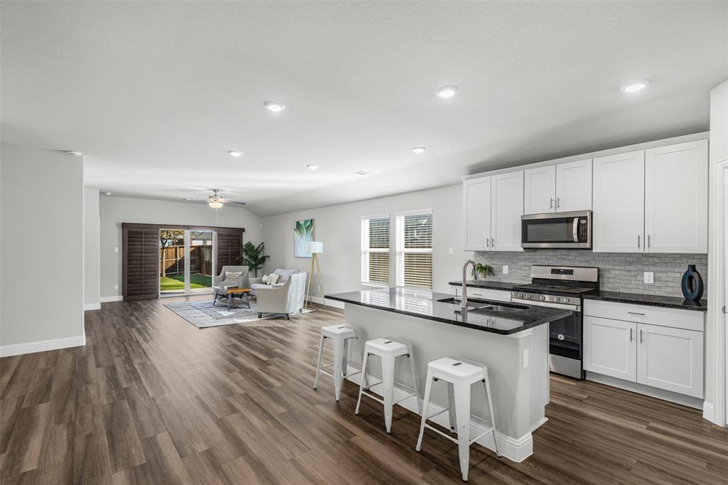 10508 Brookshire Road Fort Worth, TX 76126 - Photo 9 of 31 Kitchen featuring white cabinets, appliances with stainless steel finishes, an island with sink, a kitchen bar, and recessed lighting