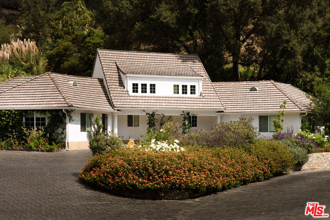 3100 Mandeville Canyon Road Los Angeles, CA 90049 - Photo 20 of 23 a view of a white house with a flower garden