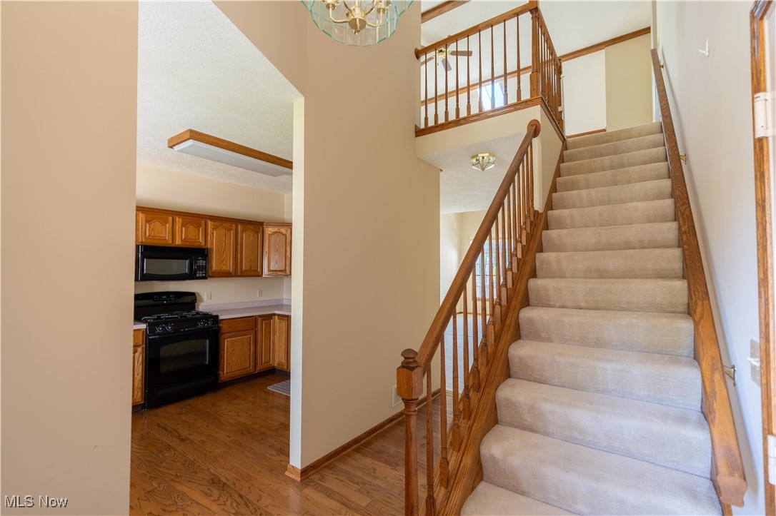2603 Charing Cross Road Northwest Canton, OH 44708 - Photo 2 of 24 Stairs featuring a towering ceiling, hardwood / wood-style flooring, and a notable chandelier