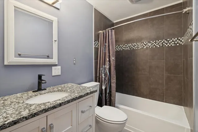 a bathroom with a granite countertop sink toilet and shower