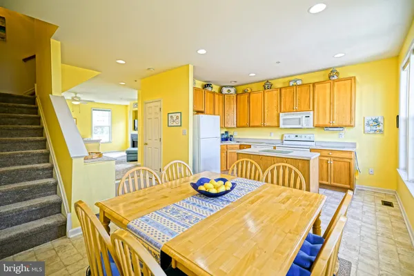a kitchen with stainless steel appliances granite countertop a sink a stove a dining table and chairs