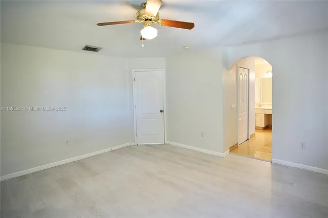 an empty room with a windows and ceiling fan