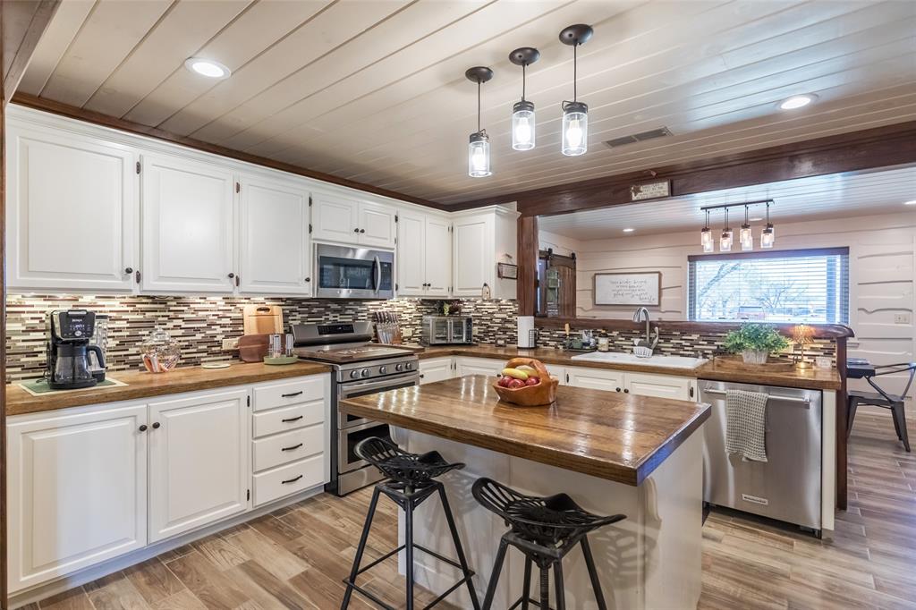 304 South Ave H Avenue Haskell, TX 79521 - Photo 10 of 38 a kitchen with stainless steel appliances granite countertop a stove top oven a sink dishwasher and white cabinets with wooden floor