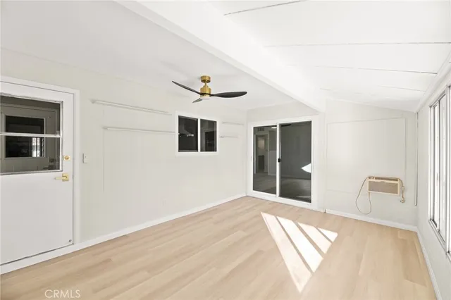 a view of an empty room with window and wooden floor