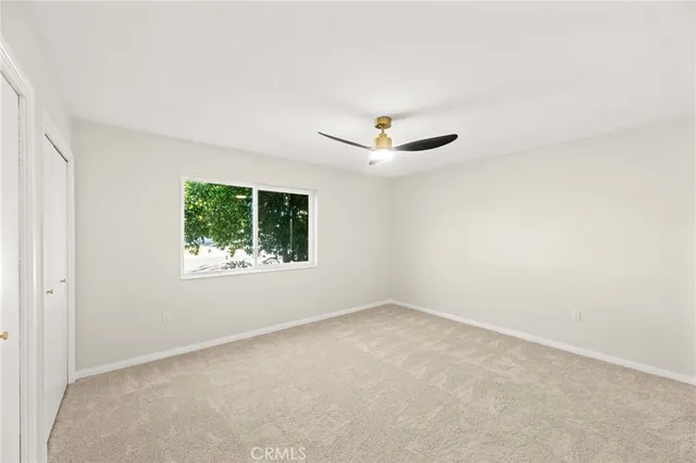 an empty room with a window and a fan