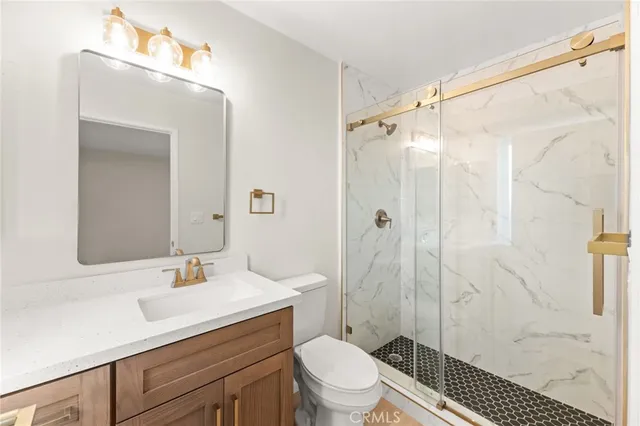 a bathroom with a sink a mirror a toilet and shower