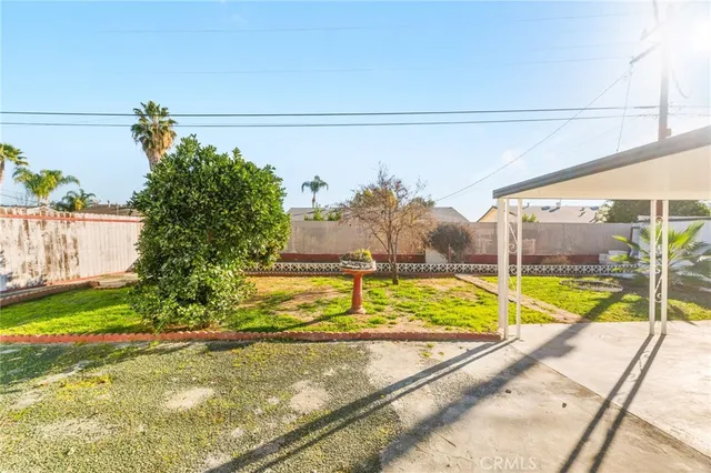 a view of a white house next to a yard with large trees