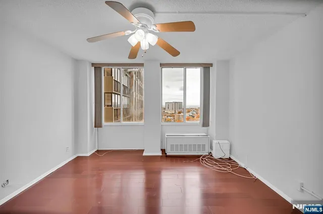 an empty room with windows and fan