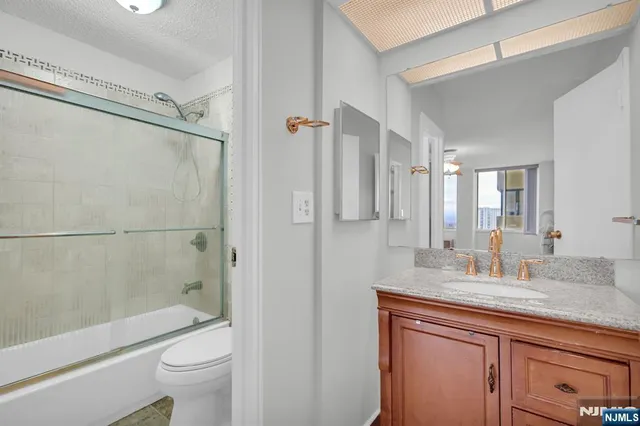 a bathroom with a granite countertop sink toilet and shower
