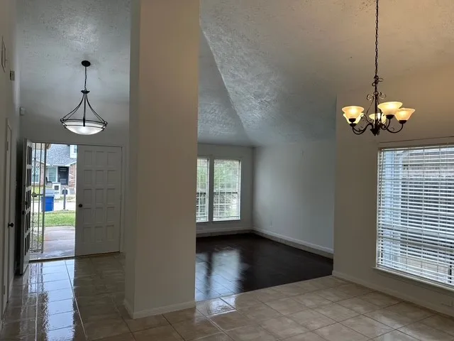 a view of a room with a chandelier and wooden floor