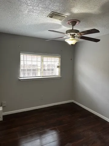 a view of empty room with wooden floor fan and windows