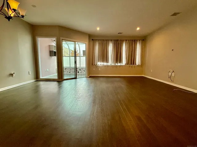 a view of an empty room with glass door and wooden floor