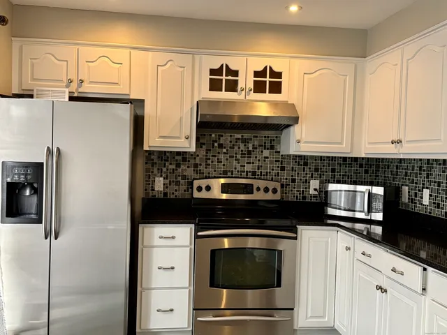 a kitchen with stainless steel appliances granite countertop a refrigerator and a stove