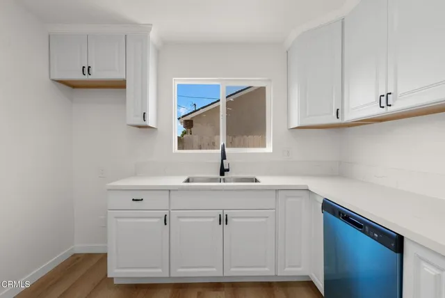 a kitchen with white cabinets and sink