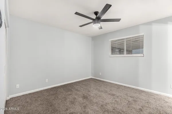 an empty room with a window and a fan