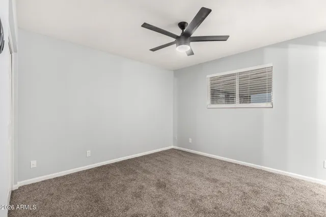 an empty room with a window and a fan