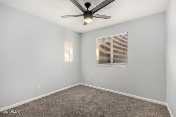 an empty room with a window and a ceiling fan